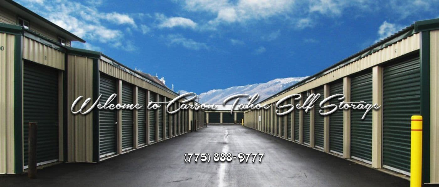 Rows of green roll-up drive-up storage doors at Carson Tahoe Self Storage with snow-capped mountains beyond